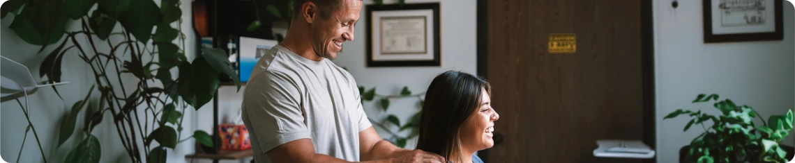 Dr. Michael VanDerschelden, DC checking a seated patient's neck and shoulders during an examination