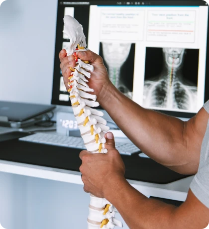Dr. Michael VanDerschelden, DC holding a spine model in front of a monitor showing a patient's cervical X-rays