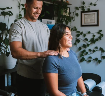 Dr. Michael VanDerschelden resting his hands on the shoulders of a seated patient while explaining a technique
